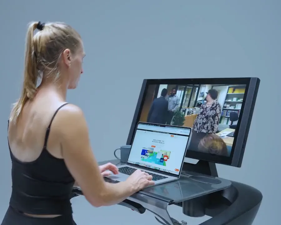 A woman typing on a laptop mounted on the Aviron Treadmill WalkDesk while walking